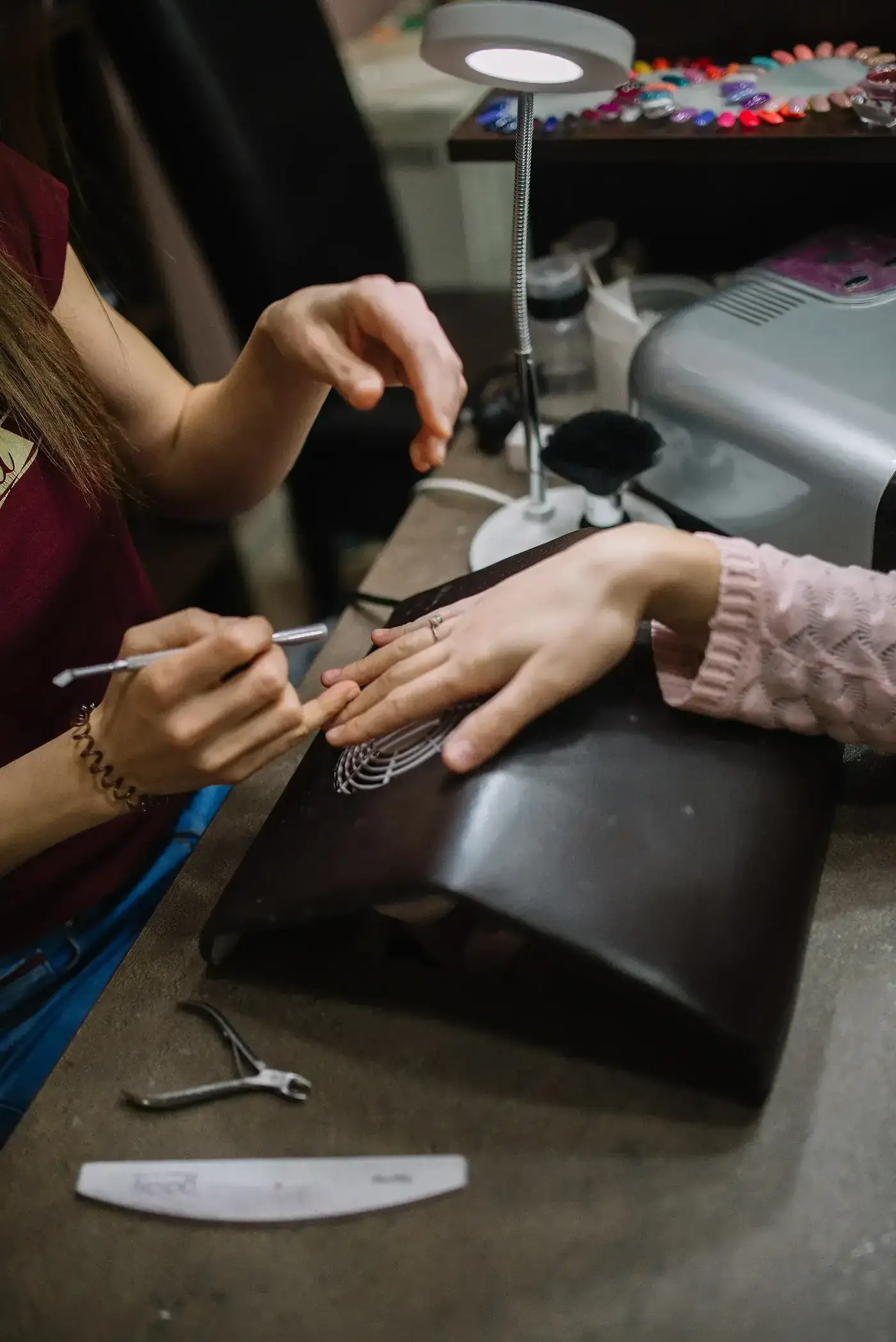 Técnica de uñas realizando un diseño de manicura sobre la mesa de trabajo del salón